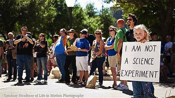 A protest of GMOs, in which a girl holds a sign that says, "I am not a science experiment"