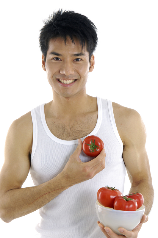 a photo of a young Asian man with a bowl of tomatoes and holding one against his heart.